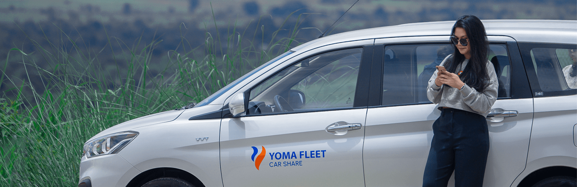 Satisfied young business man using Yoma Car Share app with smart phone in car